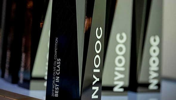 Trophies from the 2019 World Olive Oil Competition labeled 'Best in Class' and 'NYIOOC'. - Olive Oil Times