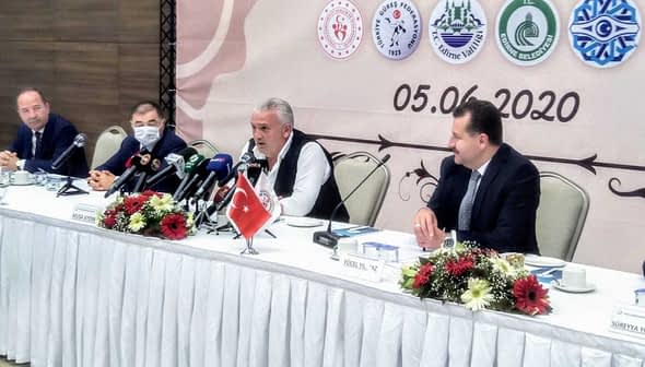 Group of officials seated at a table during a press conference with microphones and a Turkish flag. - Olive Oil Times
