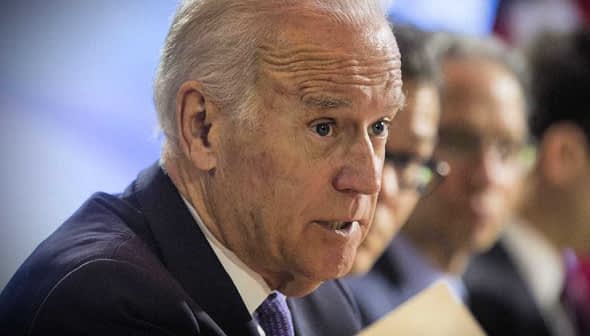 A man in a suit speaking during a conference, holding a document in his hand. - Olive Oil Times