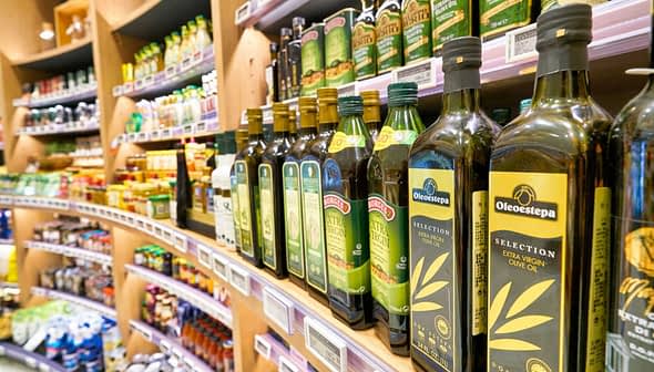 Various bottles of olive oil displayed on a shelf in a grocery store. - Olive Oil Times