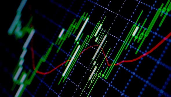 Close-up of a stock market chart displaying candlestick patterns and moving averages in green and red. - Olive Oil Times