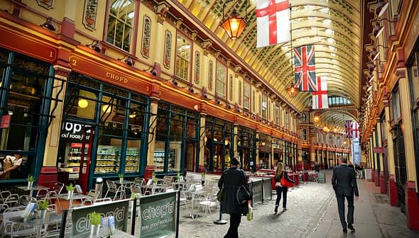 Interior view of a historic market featuring flags and people walking through. - Olive Oil Times