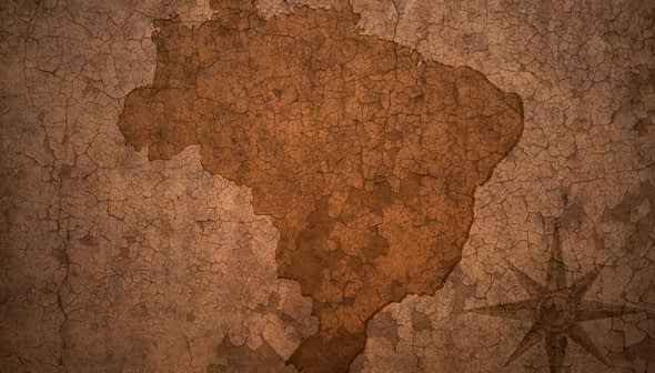 Silhouette map of Brazil displayed on a textured, cracked brown background. - Olive Oil Times