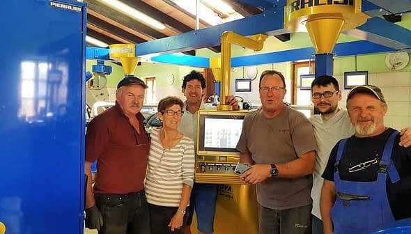 Six individuals standing in an olive oil production facility near machinery and equipment. - Olive Oil Times
