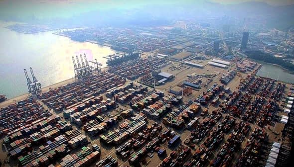 Aerial view of a busy container port with numerous shipping containers stacked. - Olive Oil Times