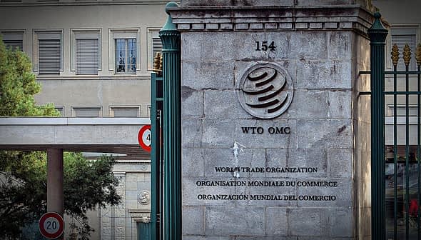 Sign of the World Trade Organization located at its headquarters with multiple languages displayed. - Olive Oil Times