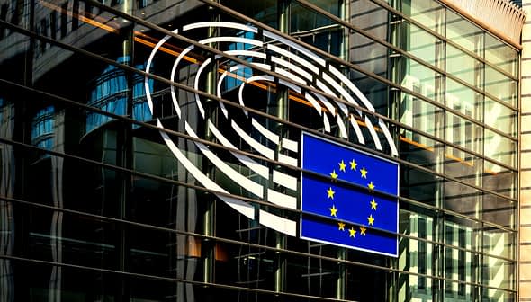 European Union flag displayed on the glass exterior of a building with circular design elements. - Olive Oil Times