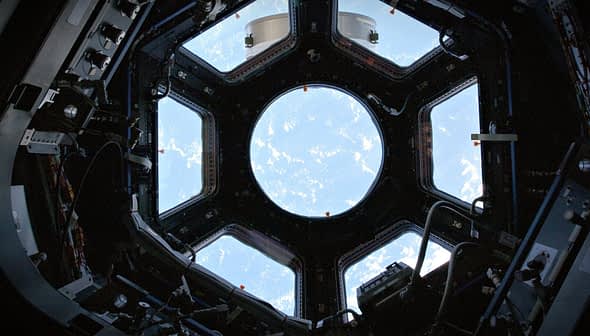 Interior view of the International Space Station's Cupola with a circular window showing Earth. - Olive Oil Times