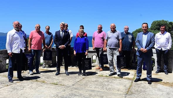 A group of individuals standing together outdoors with a clear blue sky in the background. - Olive Oil Times