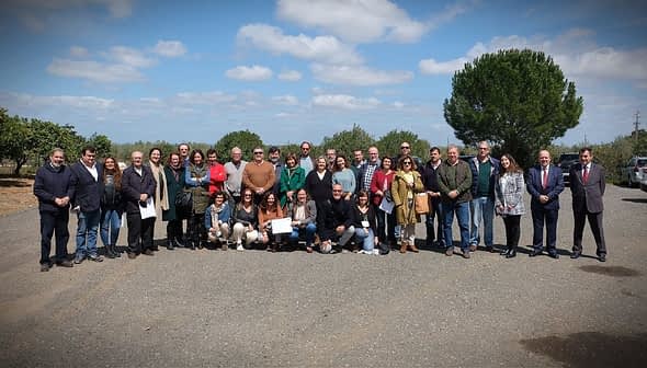 Group photo of a diverse gathering of people standing outdoors in a rural setting. - Olive Oil Times