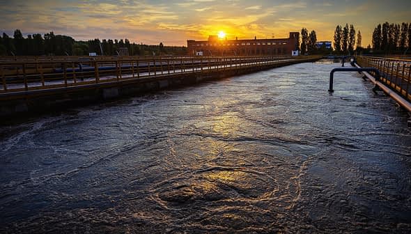 Water treatment facility with a view of the sunset reflecting on the water surface. - Olive Oil Times