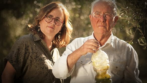 A man and a woman standing together, with the man holding an olive oil bottle in his hand. - Olive Oil Times