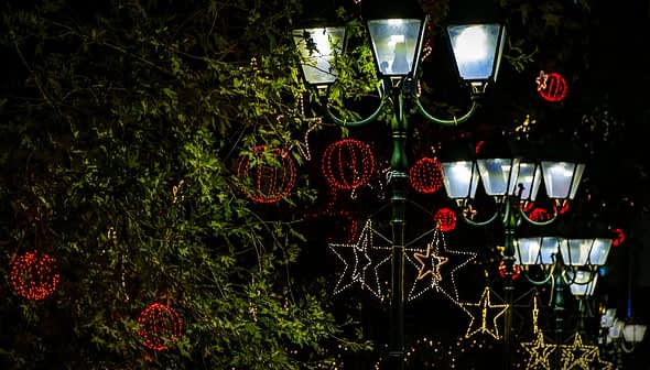 Street lamps adorned with decorative lights and ornaments during the holiday season. - Olive Oil Times