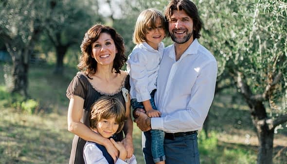 A family of four posing together in an olive grove, with two adults and two children. - Olive Oil Times