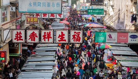 A busy street market in Hong Kong filled with numerous stalls and a large crowd of people. - Olive Oil Times