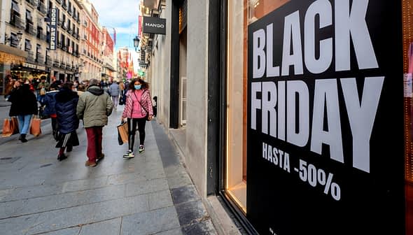 Large sign displaying 'Black Friday' with discount information on a city street. - Olive Oil Times
