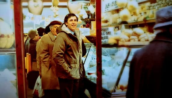 Two men standing in a market with shelves displaying various food items and products. - Olive Oil Times