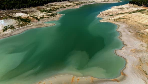 Aerial view of a calm water body with varying shades of green and blue. - Olive Oil Times