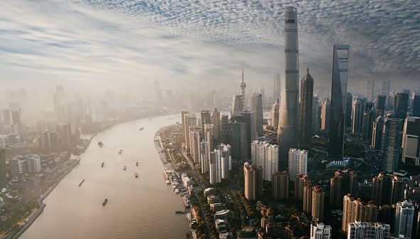 Aerial view of Shanghai skyline featuring tall buildings and a river flowing through the city. - Olive Oil Times