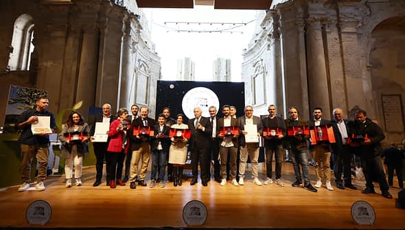 Grupo de personas sosteniendo premios en el escenario durante una ceremonia en un edificio histórico. Olive Oil Times