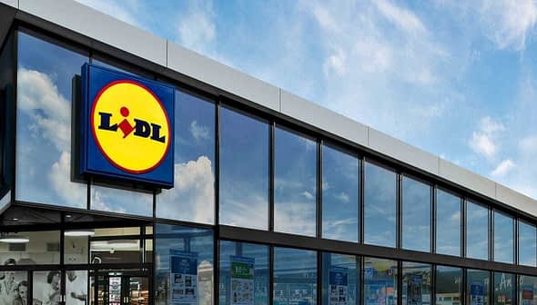 Vue extérieure d'un bâtiment de supermarché Lidl avec de grandes baies vitrées et un logo bien visible. - Olive Oil Times