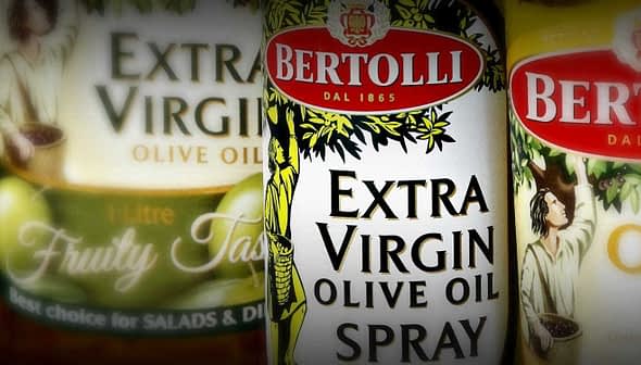Три пляшки оливкової олії Bertolli Extra Virgin та спрею з оливковою олією з чіткими етикетками та дизайном. - Olive Oil Times