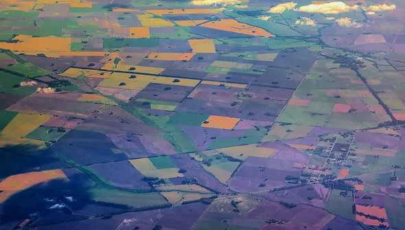 Çeşitli renk ve desenlerdeki tarım alanlarının patchwork'ünü gösteren hava görüntüsü. - Olive Oil Times