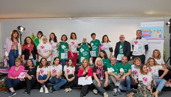 Um grupo de indivíduos posando juntos no evento Race for the Cure em Roma, vestindo camisetas combinando. - Olive Oil Times