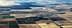 Aerial view of patchwork agricultural fields with varying colors and patterns. - Olive Oil Times