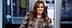Woman with long brown hair wearing a floral jacket and smiling at the camera. - Olive Oil Times