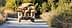 A trailer loaded with burlap bags being pulled on a dirt road surrounded by greenery. - Olive Oil Times