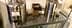 Two stainless steel dispensers labeled for olive oil and vinegar on a table with utensils. - Olive Oil Times