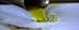 Stream of green olive oil pouring from a metal spout onto a surface. - Olive Oil Times