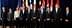 Group of ten political leaders posing for a photo at an international summit with flags in the background. - Olive Oil Times
