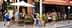 Des gens dînent dehors dans un restaurant avec des parasols et une façade en briques dans une rue. - Olive Oil Times