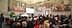 A large audience seated in a historical hall with elaborate murals on the walls. - Olive Oil Times