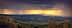 Panoramic view of rolling hills with dark clouds and sunlight breaking through in the distance. - Olive Oil Times