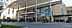 A modern commercial building featuring a glass facade and multiple banners. - Olive Oil Times