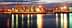 Cargo ships docked at a port with cranes illuminated at twilight. - Olive Oil Times