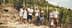 Group of people posing together in a vineyard with grapevines in the background. - Olive Oil Times