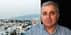 Ein Mann mit grauem Haar und gestreiftem Hemd posiert für ein Porträt mit einer Stadtlandschaft im Hintergrund. - Olive Oil Times
