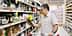 Мужчина держит бутылку оливкового масла, делая покупки в продуктовом магазине. Olive Oil Times