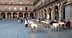 Outdoor dining area with tables and chairs set up in a plaza, featuring people seated and a server attending to guests. - Olive Oil Times