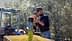 A man pouring freshly harvested olives into a container during the olive harvesting process. - Olive Oil Times