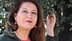 Woman with long brown hair wearing red earrings, posing outdoors with a hand on a tree branch. - Olive Oil Times