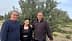 Three individuals standing together in front of an olive tree in an outdoor setting. - Olive Oil Times