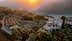 Vista aerea di un casale rustico circondato da ulivi e colline durante il tramonto. - Olive Oil Times