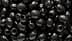 Close-up image of shiny black olives with visible holes. - Olive Oil Times
