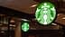 Placa com logotipo iluminado da Starbucks com fundo verde e desenho de sereia branca. - Olive Oil Times