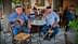 Dos hombres mayores con sombreros sentados en una pequeña mesa redonda en un café. Olive Oil Times